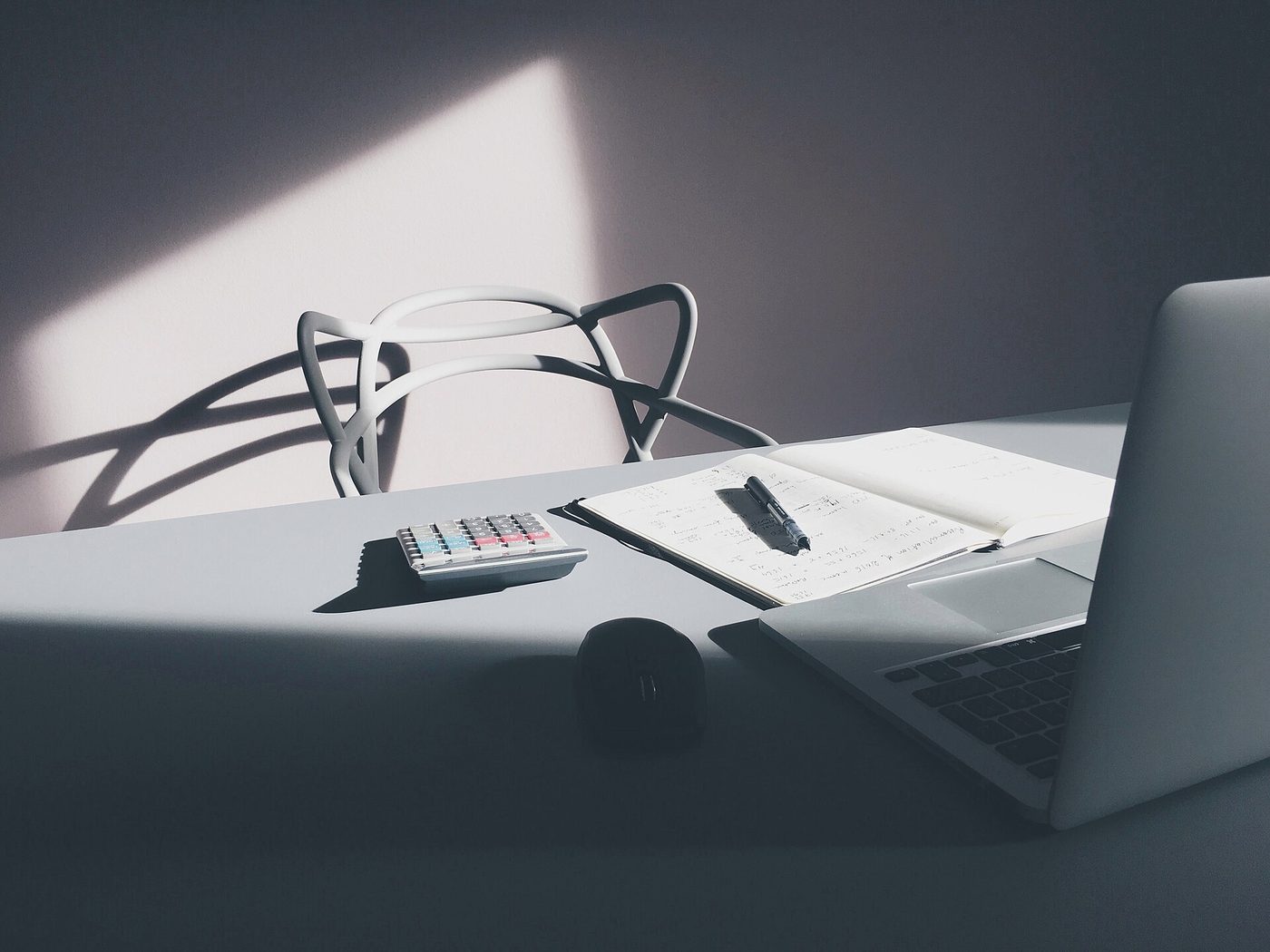 A desk with a laptop, papers and a calculator